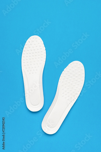 Two bright white insoles on a blue background.