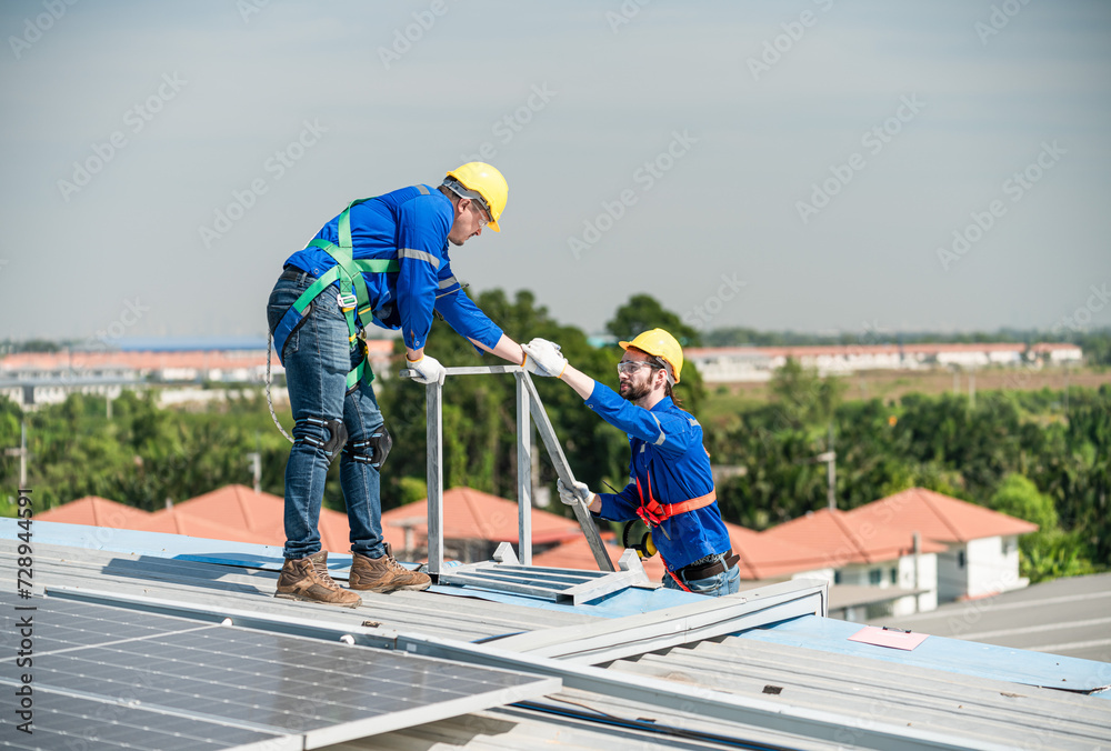 Male technicians holding solar panels on factory roofs and Engineers in helmets are helping each other as a team. Could you install an outdoor solar panel system or an Alternative solar cell.
