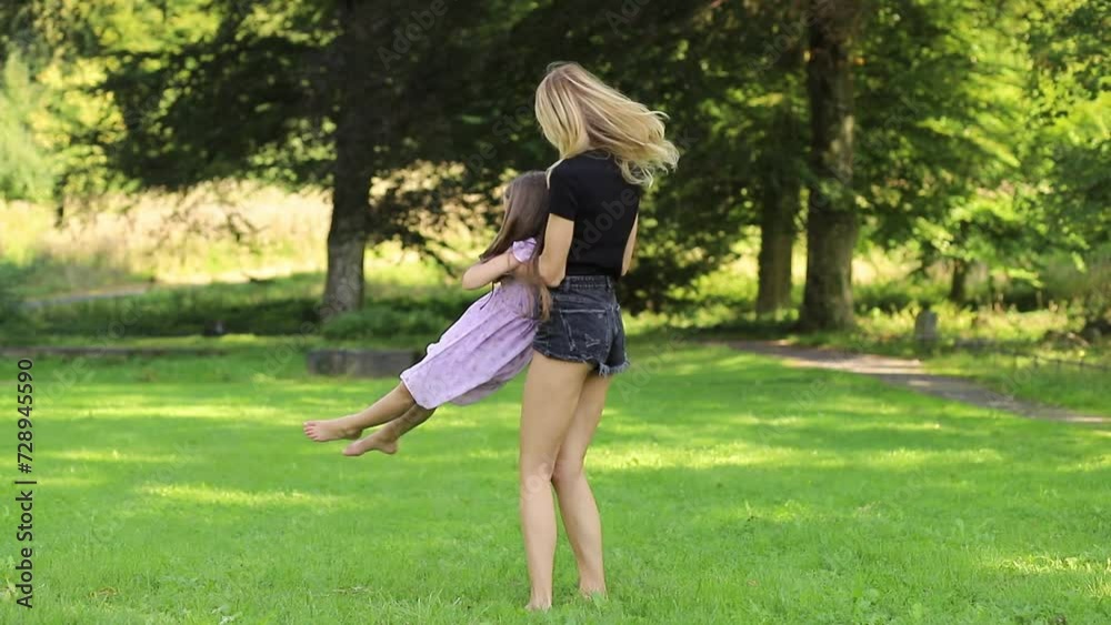 Mother twirling daughter in arms at the park Mother twirling daughter in arms at the park
