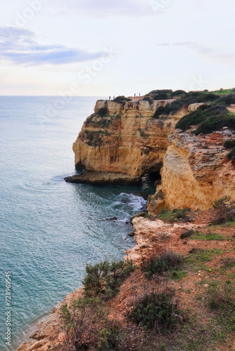 People standing on cliffs above the Atlantic Ocean on a winter day in southern Portugal.
