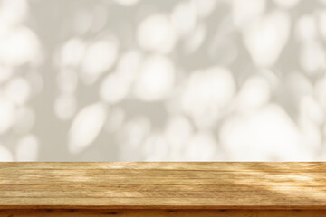 Empty wood table top on beige wall texture with tree leaves shadow background