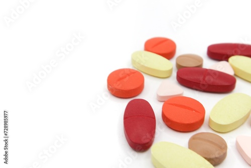 Detailed photos of oval, round and triangular shaped tablets in various colors: red, orange, yellow and cream. The photo was taken on a white background