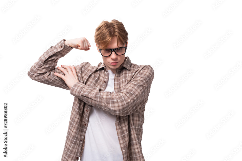 young stylish european student man with golden hair in glasses and a plaid shirt shows muscles