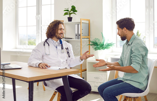Medicine, healthcare and people. Friendly doctor advises man on health maintenance and gives advice on treatment. Man in medical coat sitting in office in clinic is talking to joyful male patient. 