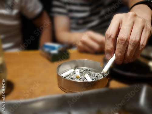 紙たばこを吸っている人が灰皿に灰を落とす