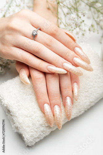 The nails are covered with pearl gel polish on white background