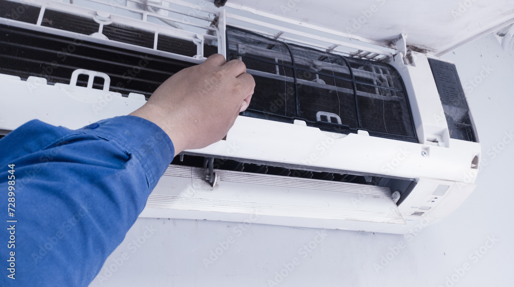 The concept of carrying out maintenance on the room air conditioning, a service technician cleaning the filter on the indoor air conditioning section,Maintenance process on the room air conditioning. The concept of carrying out maintenance on the room air conditioning, a service technician cleaning the filter on the indoor air conditioning section,Maintenance process on the room air conditioning.