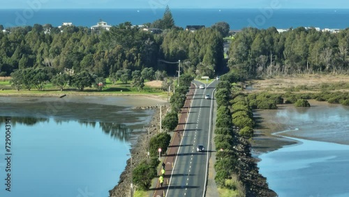Aerial: Road over harbour into the holiday town of Omaha, near Warkworth, New Zealand photo