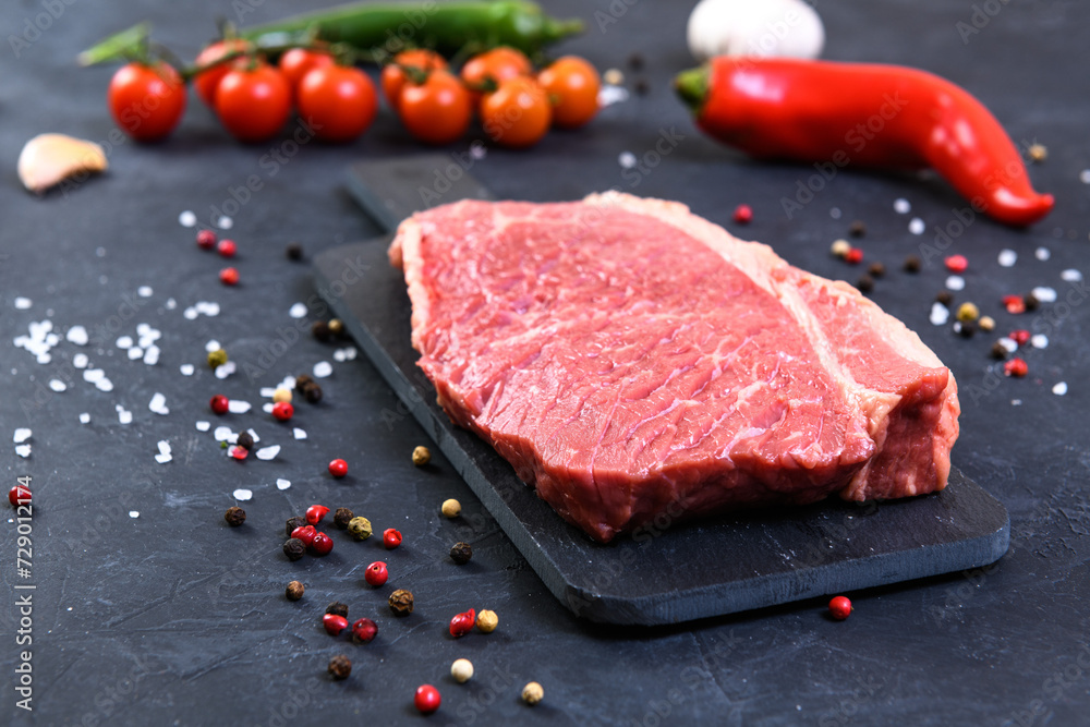 Raw fresh marbled meat and seasonings on dark background Raw fresh marbled meat and seasonings on dark background