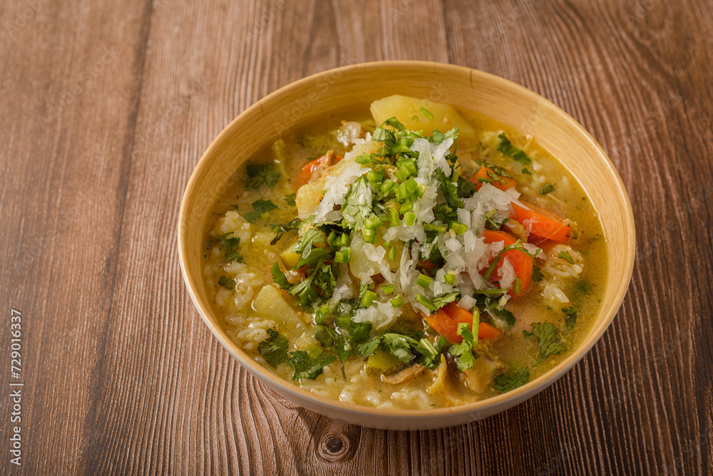 Chicken soup with vegetables in a deep bowl on a wooden table. Chicken soup with vegetables in a deep bowl on a wooden table.