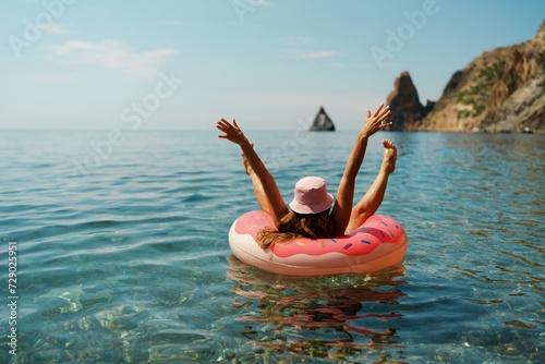 Summer vacation woman in hat floats on an inflatable donut mattress. Happy woman relaxing and enjoying family summer travel holidays travel on the sea. photo