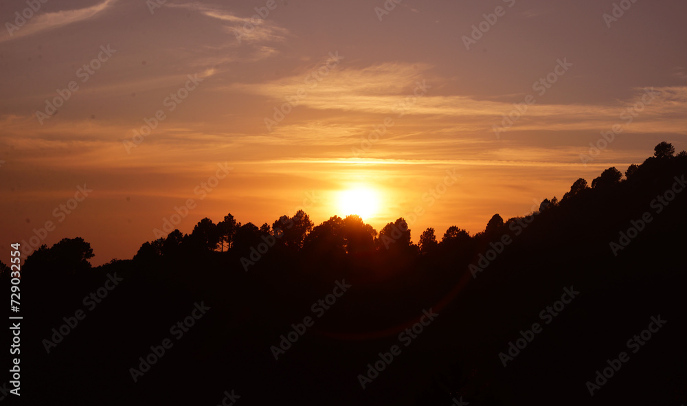 Sun setting behind the mountains with glowing flare light and dark shape of mountain on front. Sunset in the mountains wallpaper