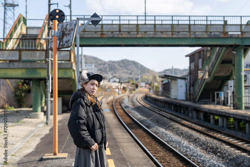 田舎の駅のホームで電車を待つ女性 田舎の駅のホームで電車を待つ女性