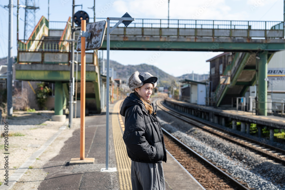 田舎の駅のホームで電車を待つ女性 田舎の駅のホームで電車を待つ女性
