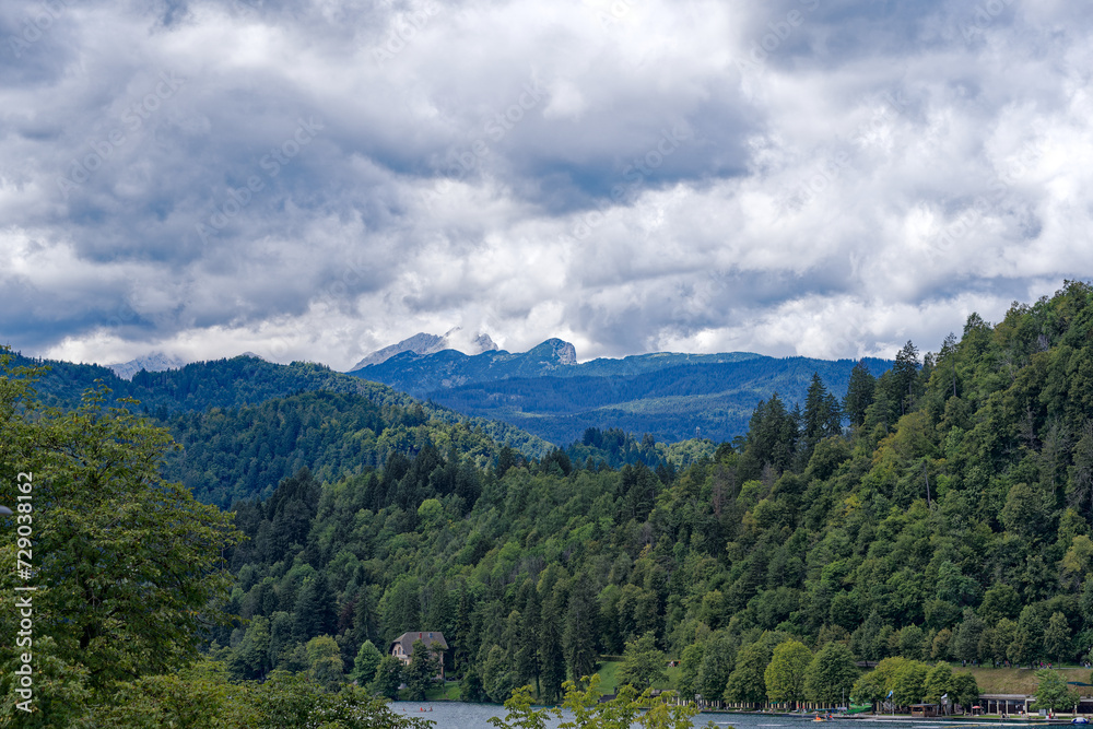 Scenic landscape at Lake Bled with woodland and the Slovenian Alps in the background on a cloudy summer day. Photo taken August 8th, 2023, Bled, Slovenia.