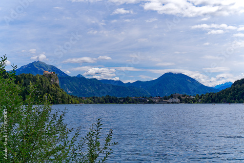 Slovenian Lake Bled with church on an island and mountain panorama with woodland in the background on a cloudy summer day. Photo taken August 8th, 2023, Bled, Slovenia.