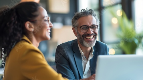 Smiling Professionals Using Laptop, Representing Teamwork and Success in Business