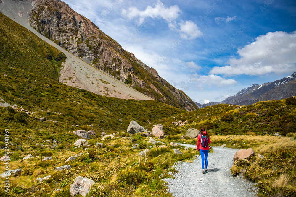 Naklejka premium hiker girl walking alongside hooker valley track toward hooker lake and mt cook, famous walk in canterbury, new zealand south island