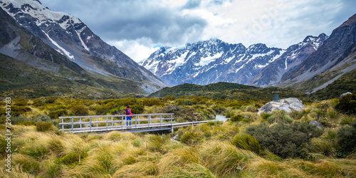 hiker girl walking alongside hooker valley track toward hooker lake and mt cook, famous walk in canterbury, new zealand south island photo