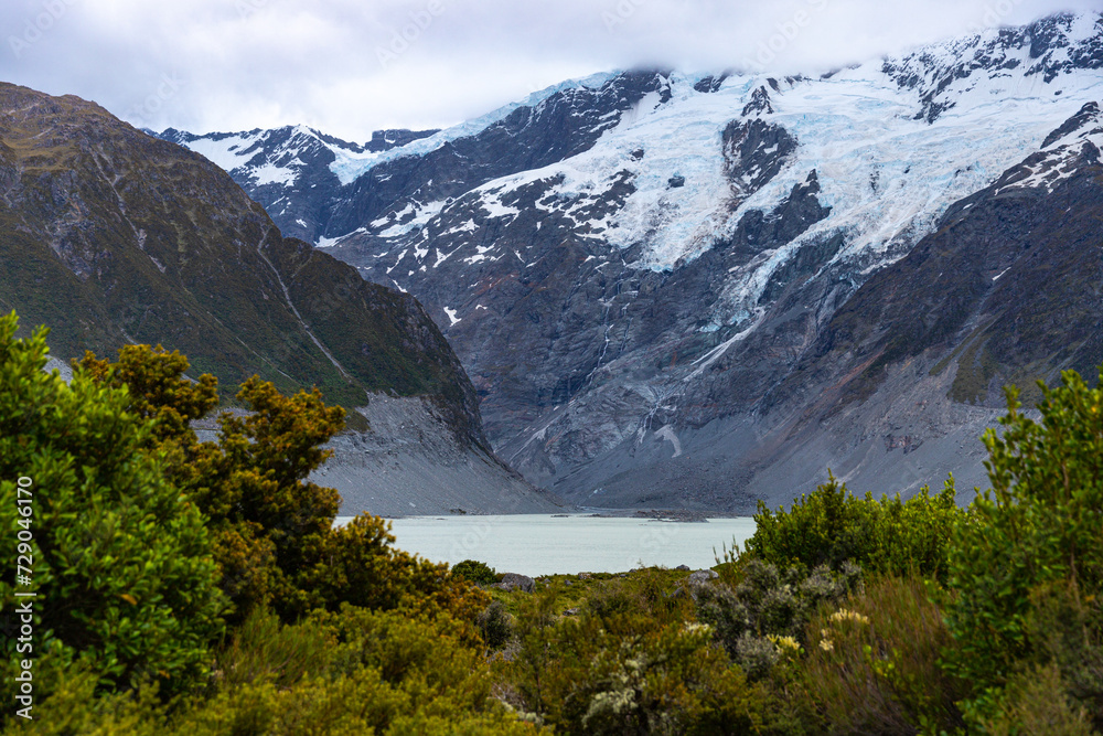 Fototapeta premium hiker girl walking alongside hooker valley track toward hooker lake and mt cook, famous walk in canterbury, new zealand south island