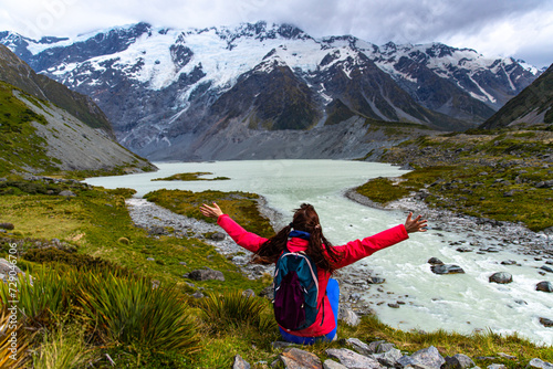 hiker girl walking alongside hooker valley track toward hooker lake and mt cook, famous walk in canterbury, new zealand south island photo