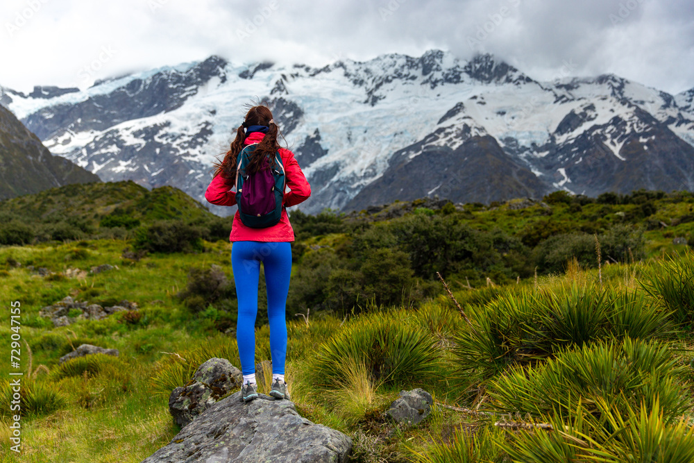 Obraz premium hiker girl walking alongside hooker valley track toward hooker lake and mt cook, famous walk in canterbury, new zealand south island