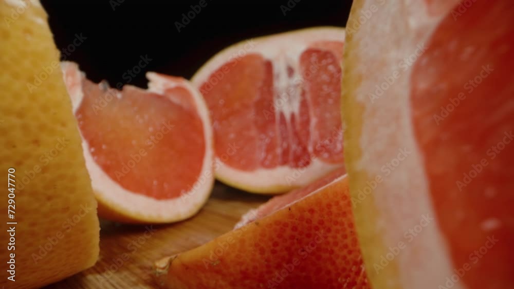 Sliced grapefruit on a wooden cutting board, the camera moves backward between the slices. Dolly slider, close up. Sliced grapefruit on a wooden cutting board, the camera moves backward between the slices. Dolly slider, close up.