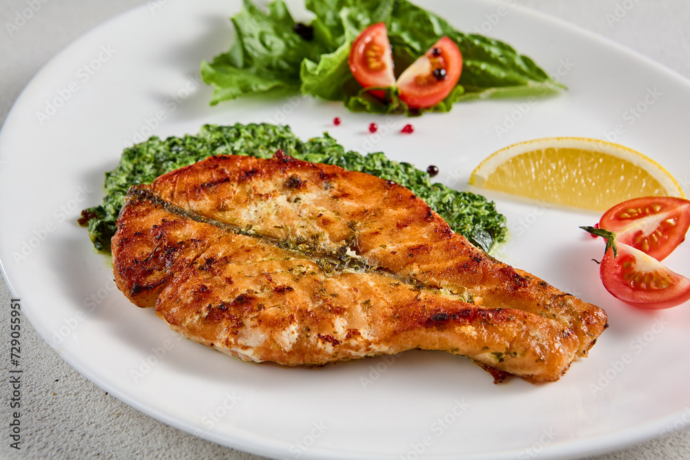 Pan-seared salmon steak with fresh spinach on white plate, perfect for healthy lifestyle and seafood cuisine presentations Pan-seared salmon steak with fresh spinach on white plate, perfect for healthy lifestyle and seafood cuisine presentations