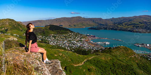 pretty hiker girl enjoying the panorama of lyttelton after finishing the hike on the bridle path from christchurch to lyttelton  beautiful view from gondola summit station, canterbury, new zealand  © Jakub