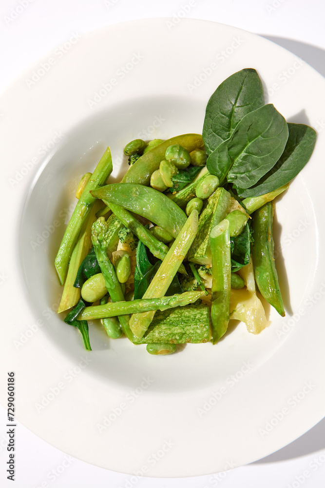 Green vegetable garnish with asparagus, zucchini, and edamame beans isolated on white background, top view Green vegetable garnish with asparagus, zucchini, and edamame beans isolated on white background, top view