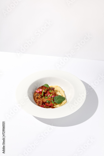 Braised beef with vegetables and mushrooms served with mashed potatoes, on an isolated white background, a hearty meal