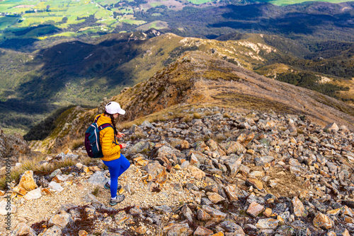 hiker girl walking down the steep trail from the top of mount somers in canterbury, new zealand south island photo