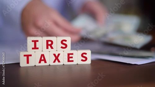 Concept of owing taxes to the Internal Revenue Service. IRS taxes word with selective focus and person paying on the background.