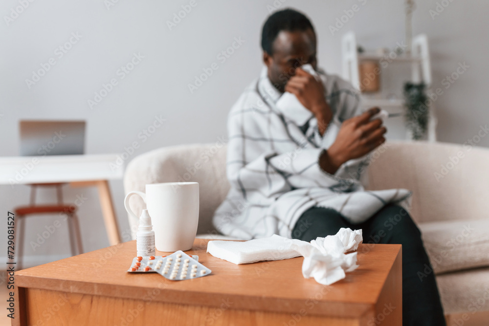 Looking at thermometer. Sick black man is at home Looking at thermometer. Sick black man is at home