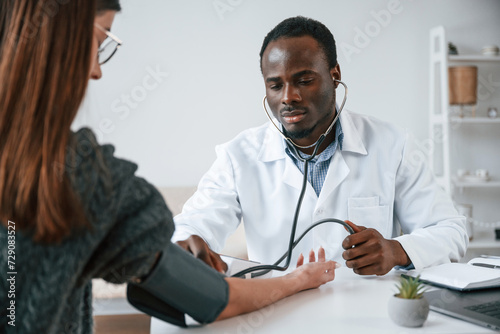 A doctor measures a young woman's blood pressure © standret