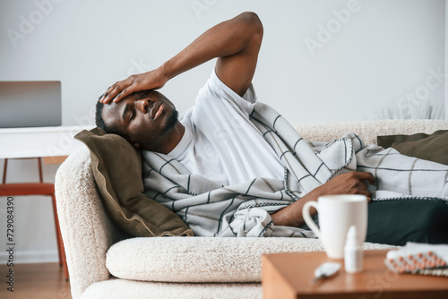 Tableau sur toile Lying down on the sofa. Sick black man is at home