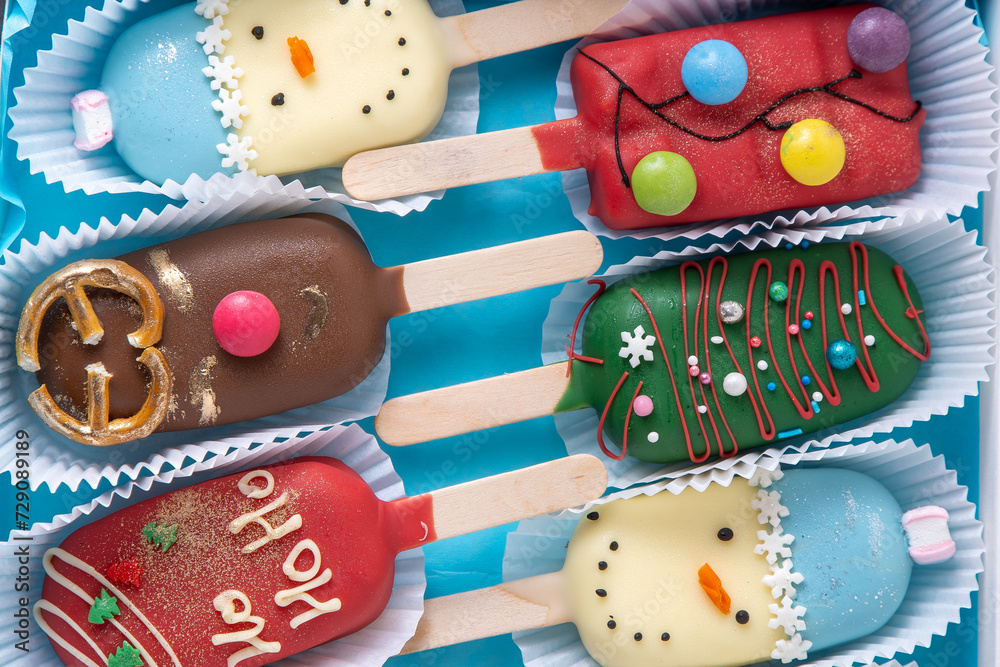 Obraz premium Christmas dessert. Sweet food. Cheesecake on a stick in the shape of ice cream. Children's treat in winter. Candy Christmas tree, snowman, deer and Santa Claus. Gingerbread cookies.