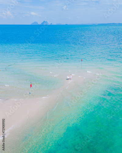 a couple of men and woman walking at a sandbar in the ocean of Koh Muk Thailand or Koh Mook