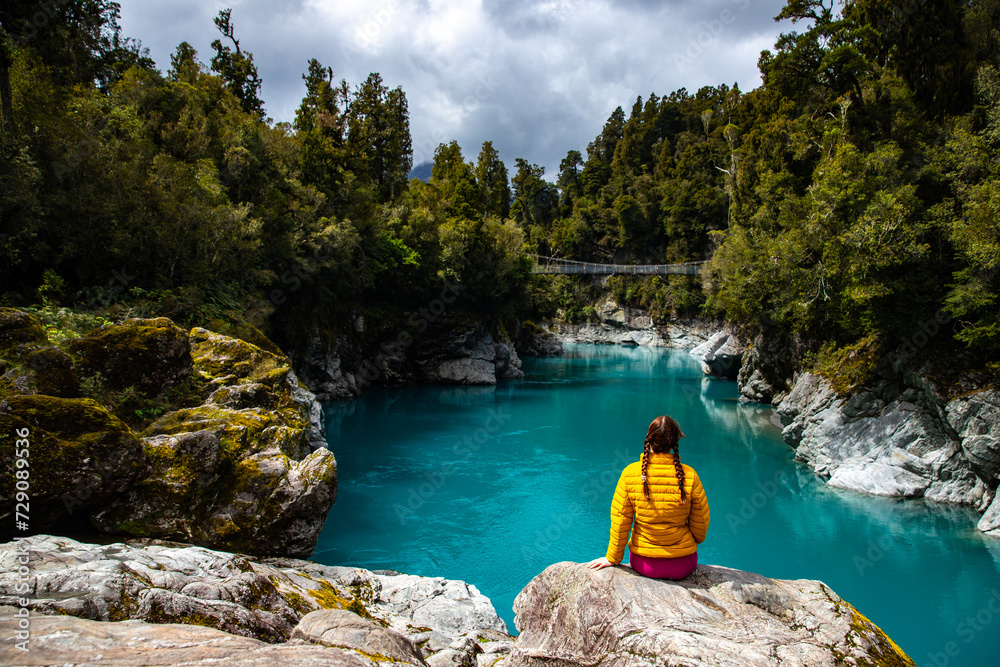 woman sitting on the rocks and enjoying unique blue water in hokitika gorge, west coast of new zealand south island woman sitting on the rocks and enjoying unique blue water in hokitika gorge, west coast of new zealand south island