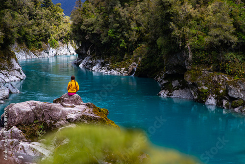 woman sitting on the rocks and enjoying unique blue water in hokitika gorge, west coast of new zealand south island