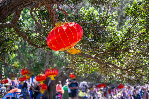 Chinese New Year lanterns hanging under the Pohutukawa trees. Crowd of people having fun at Mission Bay. Auckland.
