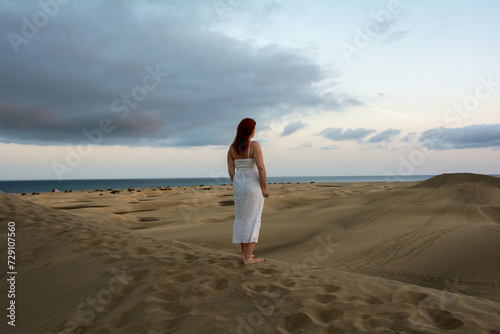 Young woman stands with her back in the sand dunes © Claudia Evans 