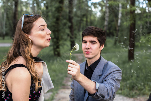 Portrait of young couple in love blowing dandelion in the park