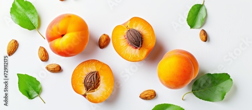 Apricot cut in half with leaves and stone, placed on a white background.