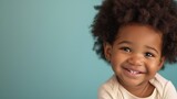 Joyful toddler captured against a soft pastel background.