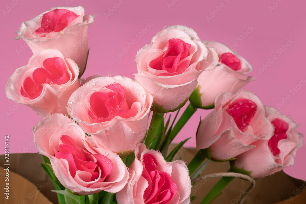 Fototapeta premium Beautiful bouquet of pink roses in paper bag on pink background, Closeup