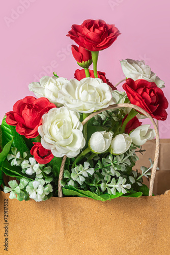 Bouquet of red and white roses in paper bag on pink background  close-up