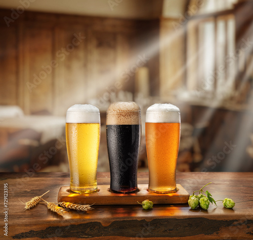Set of different glasses of chilled beer on wooden table. Blurred old-fashioned pud interior at the background.