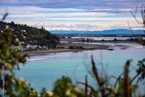 panorama of famous sumner beach in christchurch, canterbury, new zealand; beautiful beach with christchurch city and snow covered mountains in the background