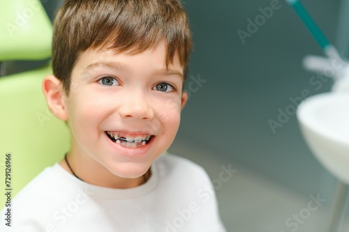 The boy inserts an orthodontic plate in his mouth photo